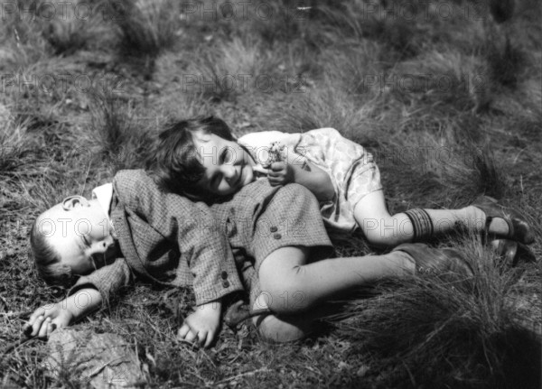 Boy and girl lying in a meadow, 1920, Two children lying relaxed in the meadow and enjoying the summer atmosphere, Historical photo