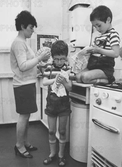 Mother and sons drying dishes, Housework, Education, 1960s, A mother and two children drying dishes in a kitchen, Historical photo