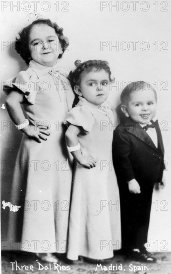 Three children from tall to short, 1920s, children in formal dress posing in front of a studio background, historical photo