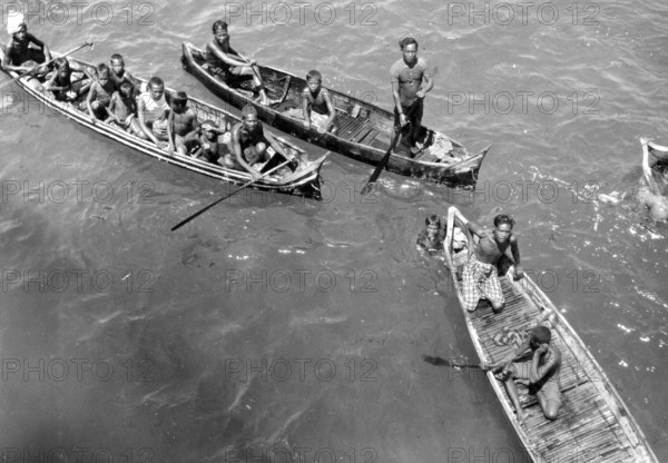 Children in catamarans, Asia, 1930s, People in boats paddling together on a river or lake, Historical photo
