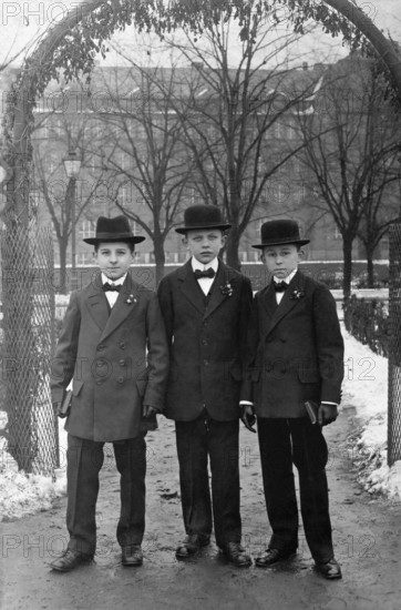 Young men, 1920s, Three boys in elegant clothes and hats stand under an arch on a snowy day, Historical photo