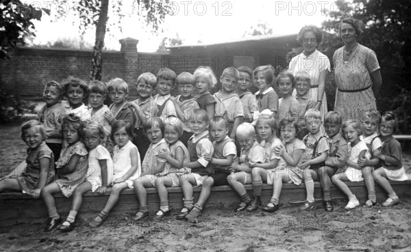 Kindergarten, 1920s, group of children and two woman outdoors, cheerful atmosphere, black and white, historical photo