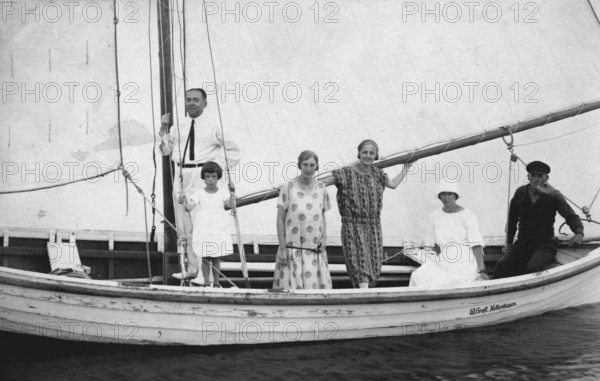 Group in sailing boat, 1920s, family standing on a sailing boat with hoisted sails, historical photo