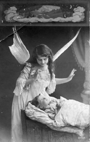 Angel at a child's bedside, 1920s, An angel watches over a sleeping child in a bed, Historical photo