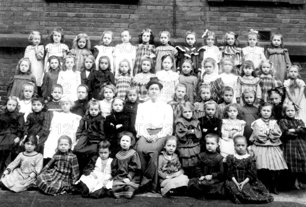 Girls school class, 1910s, Large group of girls with a teacher posing in front of a wall, Historical photo