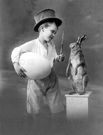 Boy with egg and rabbit, 1930s, Young pantomime with top hat presents a rabbit with magic wand and egg, historical photo