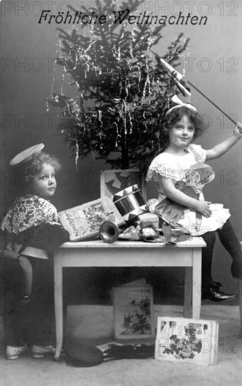 Boy and girl under a Christmas tree, 1930s, Two children sitting in front of a Christmas tree with presents and a joyful atmosphere, Historical photo