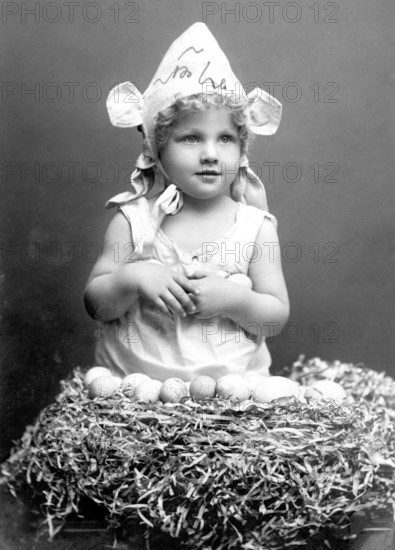 Child with Easter eggs, 1930s, Little girl in bunny costume sitting in a nest surrounded by eggs, Historical photo