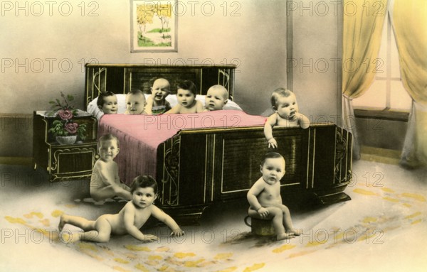 Nine babies in a bed, 1920s, Several babies crawling curiously around a large bed in a room, Historical photo