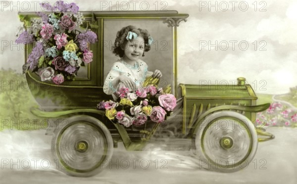 Girl in flower car, 1920s, A girl poses cheerfully from a toy car decorated with flowers, Historical photo
