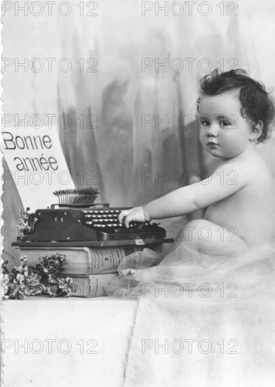 Baby writing at a typewriter, 1920s, A baby sits next to a typewriter with a French greeting, Historical photo