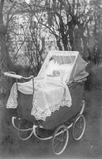 Baby in a pram, 1920s, A baby lies in a nostalgic pram outdoors, surrounded by trees, Historical photo