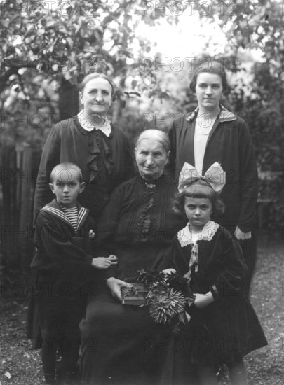 Family photo, 1920s, Three generations pose for a portrait in the garden with flower decoration, Historical photo