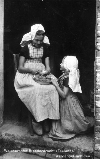 Peeling potatoes, 1920s, Two woman in traditional Seeland traditional costume peeling potatoes on the stairs of a house, Historical photo