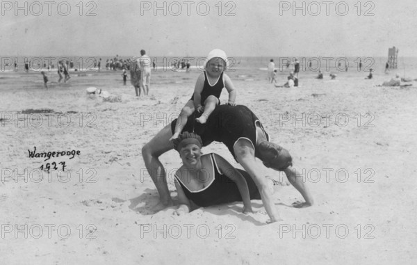 Family on the beach, Wangerooge 1927, An adult lies on the beach while a child sits on his back. The scene radiates joy, historical photo