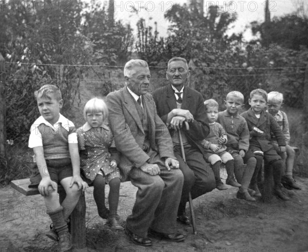 Short and tall men, 1920s, grandfather and children on an outdoor bench, symbolises family ties across generations, historical photo