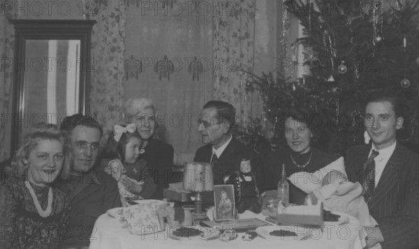Christmas party, 1930s, Christmas party with a family around a set table with presents and a Christmas tree in the background, historical photo