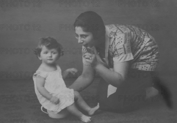 Mother with peeing childBeach, Baltic Sea, 1930s, A mother kneels next to her sitting child, both in simple, historical clothing, Historical photo