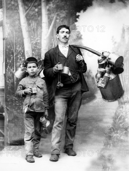 Milkman with apprentice, 1910s, adult and child with pewter cans, standing as father-son pair, historical photo