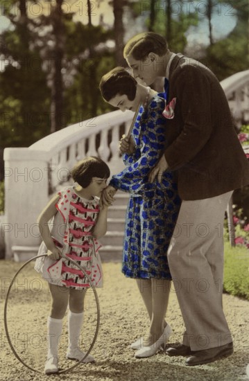 Girl kissing woman's hand, 1920s, child with a ring playing happily, watched by parents in the garden, historical photo