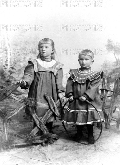 Two girls in Sunday dresses, 1920s, Two children in old-fashioned clothes in front of a painted landscape, Historical photo