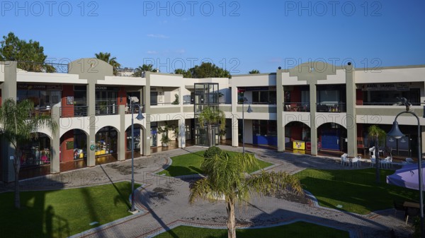 Modern shopping centre with arcades, green areas and balconies under sunny skies, Marina Centre, Kos Town, Kos, Dodecanese, Greek Islands, Greece