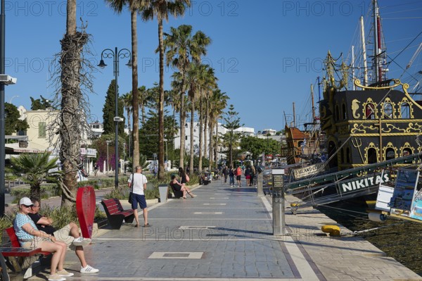 Promenade with palm trees and a sailing ship in the background, relaxed atmosphere, harbour promenade, Kos Town, Kos, Dodecanese, Greek Islands, Greece