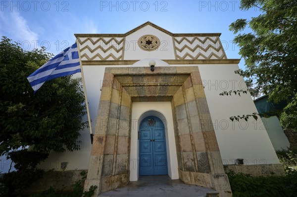 White facade of a building with Greek flag and blue door, Kos Town, Synagogue, Kos, Dodecanese, Greek Islands, Greece