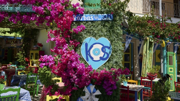 Colourfully decorated taverna with flowers and heart-shaped kos sign, sunny atmosphere, Platia Diagora, Kos Town, Kos, Dodecanese, Greek Islands, Greece