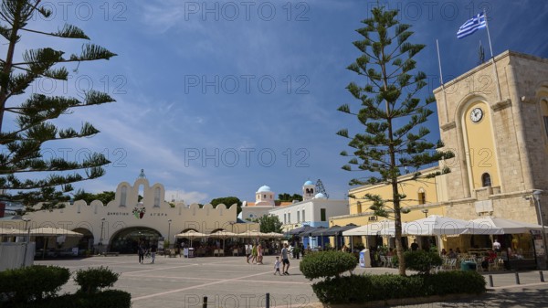 Public square with cafés and striking architectural elements under a blue sky, Eleftherias Square, Kos Town, Kos, Dodecanese, Greek Islands, Greece