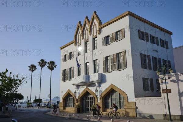 Imposing building in a Mediterranean setting with palm trees and cyclists under a bright blue sky, boutique hotel Albergo Gelsomino, 5-star hotel, Kos Town, Kos, Dodecanese, Greek Islands, Greece