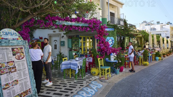 Guests sitting outside in front of a tavern decorated with flowers in kos, friendly atmosphere, Platia Diagora, Kos town, Kos, Dodecanese, Greek islands, Greece