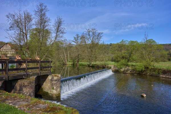 A weir in the river leads to a small waterfall, surrounded by trees, spring, Obersinn, Sinntal, Spessart, Bavaria, Germany