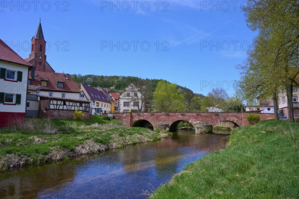 Picturesque small town view with river Saale, bridge and half-timbered houses under blue sky, Gräfendorf, Saale valley, Main Spessart district, Bavaria, Germany