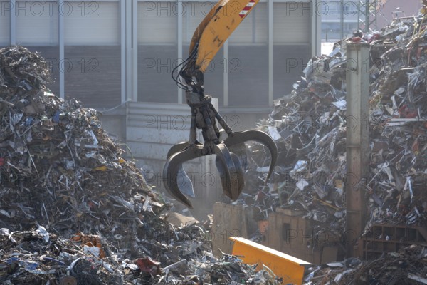 Hydraulic crane lifts scrap metal at the scrap yard