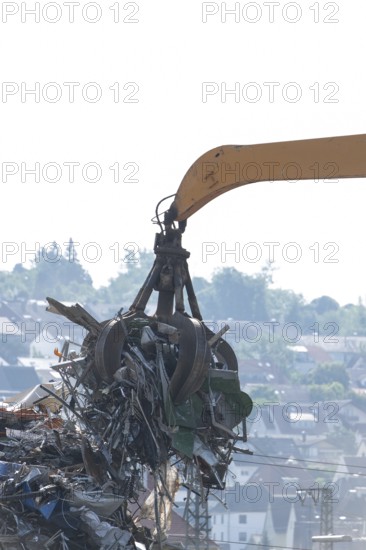 Hydraulic crane lifts scrap metal at the scrapyard in the background a city