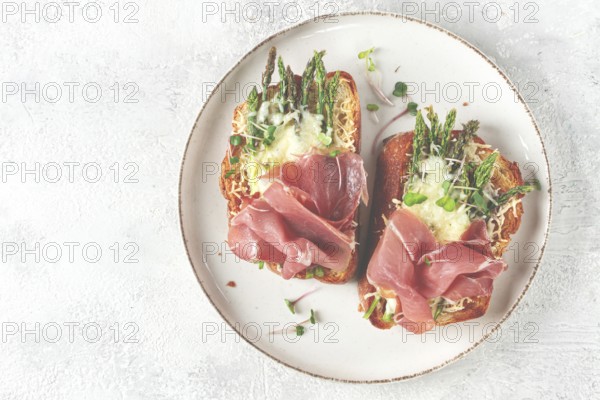 Open sandwiches with asparagus and prosciutto, with cheese, breakfast, on a plate