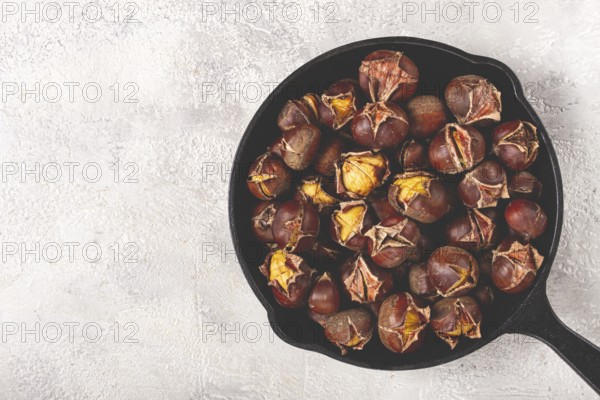 Roasted chestnuts, in an iron pan, wooden table, top view, no people, rustic style