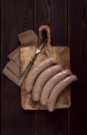 Raw sausages in English with bacon, for grilling, on a cutting board, top view, no people
