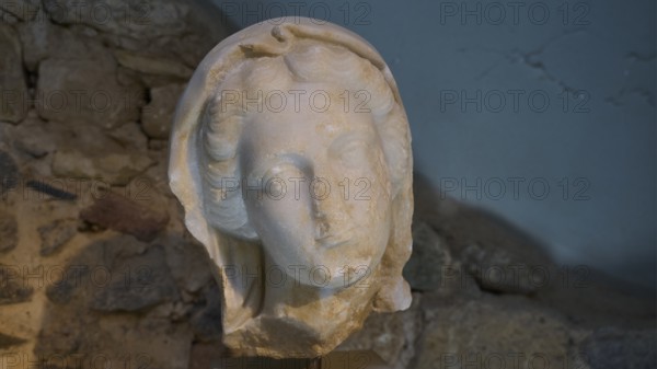 ©Udo Rein, Ancient stone sculpture of a head in front of a rock face, Faustina, Casa Romana, Kos Town, Kos, Dodecanese, Greek Islands, Greece