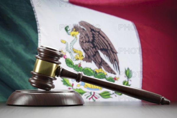 Wooden gavel resting on table in front of mexican flag
