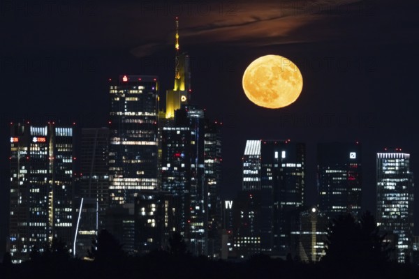 The full moon, known as the strawberry moon in June, passes over the Frankfurt banking skyline, Frankfurt am Main, Hesse, Germany