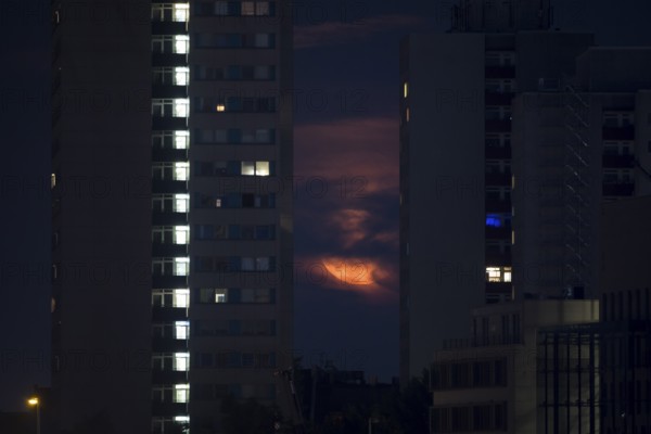 The rising strawberry moon appears between two skyscrapers in Berlin Mitte, Berlin, 11.06.2025