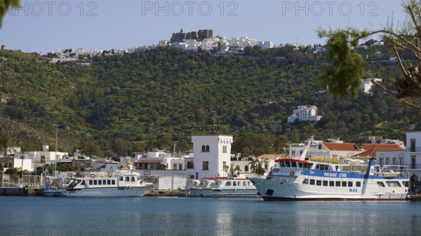 Harbour with ferries in front of green mountains and blue sea, town on the shore, Skala, harbour, Chora, Patmos, Dodecanese, Greek Islands, Greece
