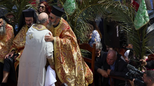 A priest embraces another clergyman during a religious ceremony amidst palm trees, Orthodox ceremony, monks of St John's Monastery, ceremonial foot washing, procession, Maundy Thursday, Megali Pempti, Chora, Patmos, Dodecanese, Greek Islands, Greece
