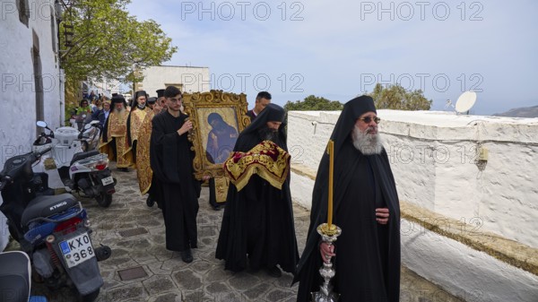 Priests in black robes and icon bearers walk along a wall during a religious procession, Orthodox ceremony, monks of St John's Monastery, ceremonial washing of feet, procession, Maundy Thursday, Megali Pempti, Chora, Patmos, Dodecanese, Greek Islands, Greece