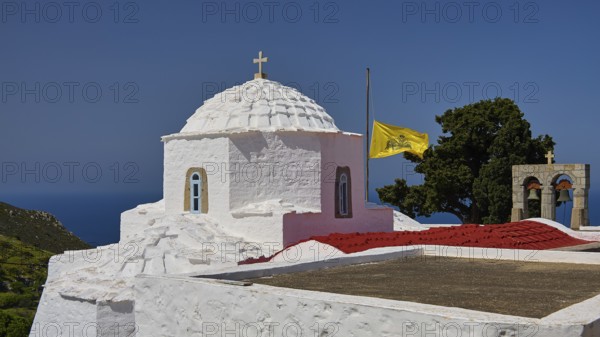 White chapel with dome and waving yellow banner, sea and trees in the background, church, Chora, World Heritage Site 1999, Patmos, Dodecanese, Greek Islands, Greece