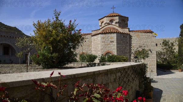 Stone church with tiled roof, surrounded by a blooming garden under a blue sky, woman's monastery, Evangelismou Monastery, Patmos, Dodecanese, Greek Islands, Greece