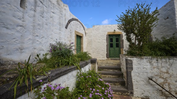 Inner courtyard with whitewashed walls, green doors and flowering plants, Monastery of the Revelation, Moni tis Apokalipsis, World Heritage Site 1999, Patmos, Dodecanese, Greek Islands, Greece