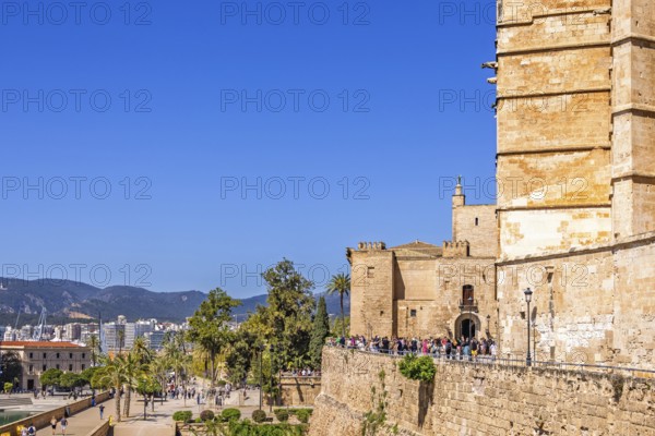View at Palma city with tourists in the sunshine outside the famous old Palma Cathedral, Palma de Mallorca, Mallorca, Spain